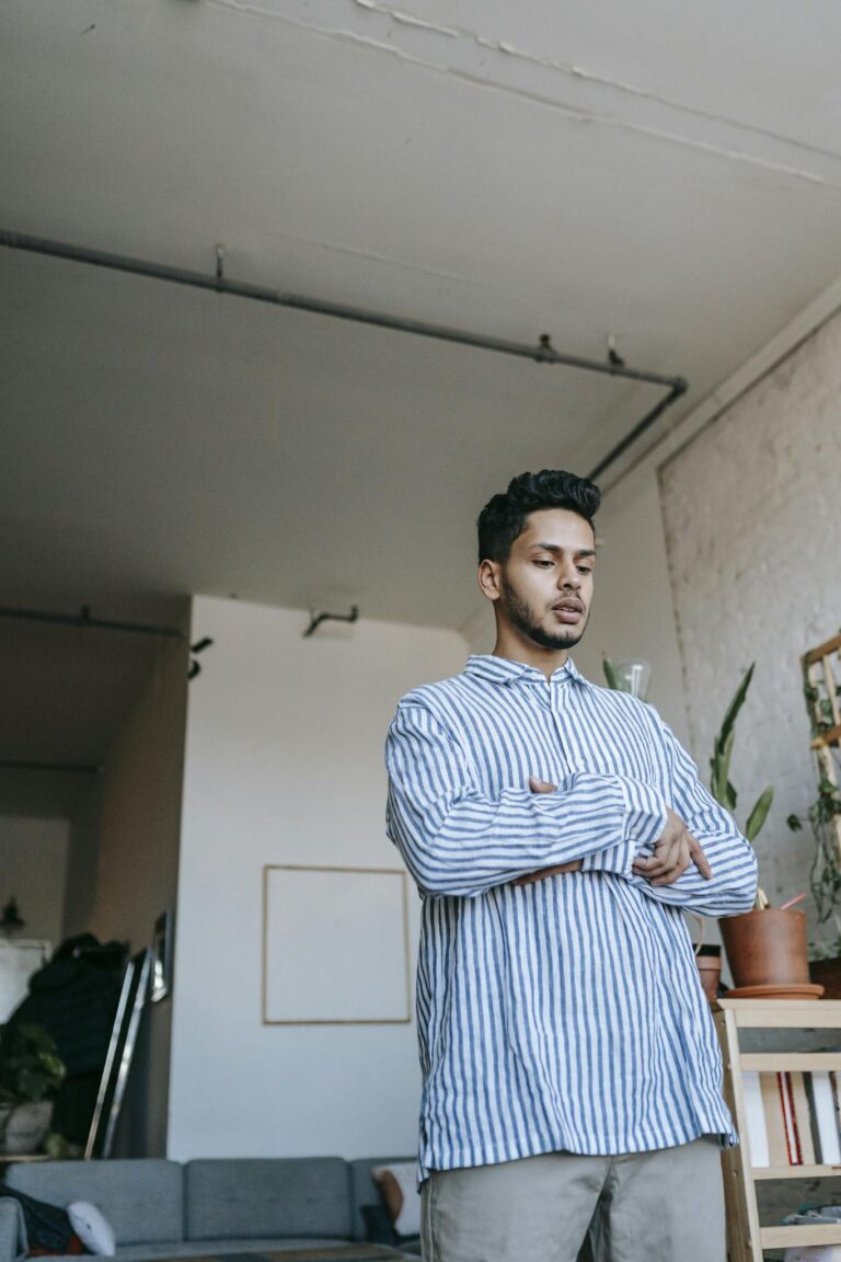 A young man in casual wear praying inside a minimalist home interior, showcasing daily religious practice.